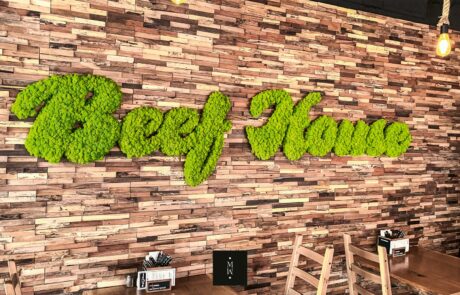 MoosMoos – Logo Restaurant Beef House aus apfelgrünem Islandmoos Logo des Restaurants Beef House aus apfelgrünem Islandmoos als Referenzbildan einer Ziegelwand