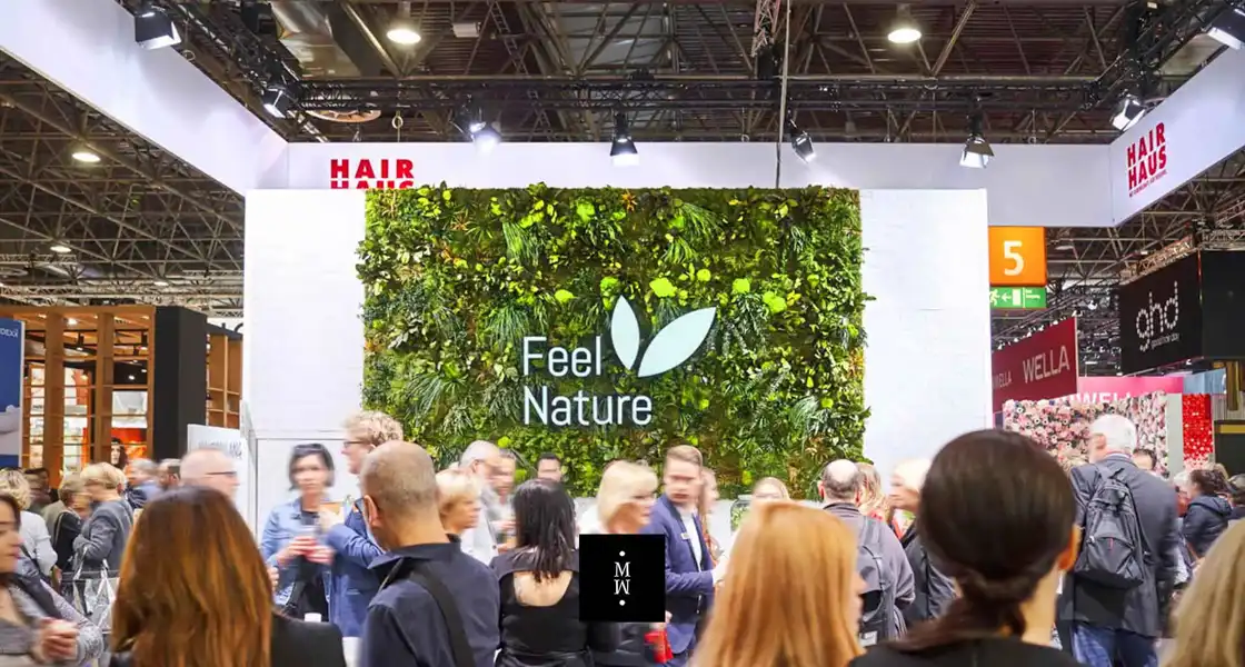 a group of people standing in front of a wall with plants
